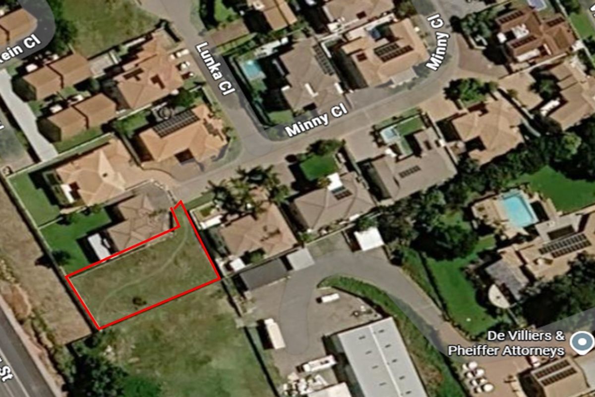 Aerial view of a vacant residential plot highlighted in red, situated within an established suburban neighborhood.
