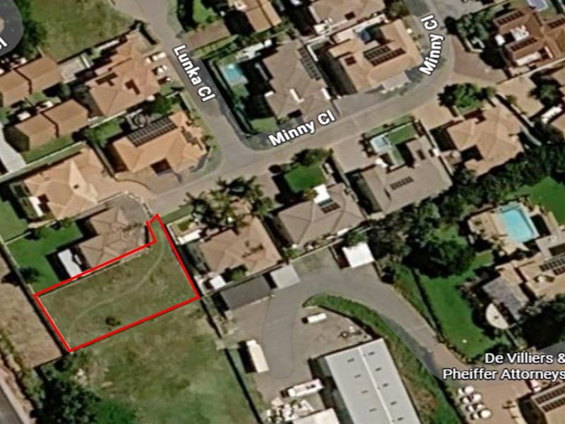 Aerial view of a vacant residential plot highlighted in red, situated within an established suburban neighborhood.
