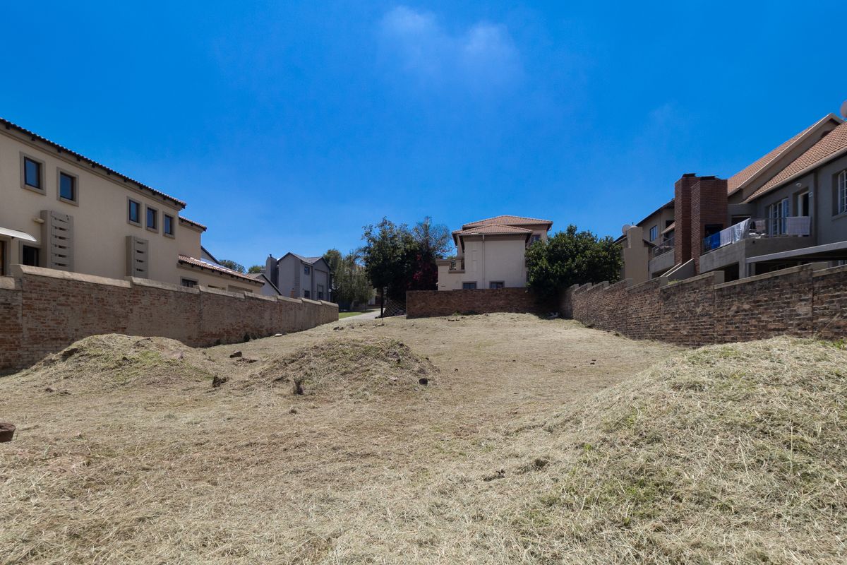 A vacant residential plot situated between existing brick boundary walls, offering a clear space for potential development.