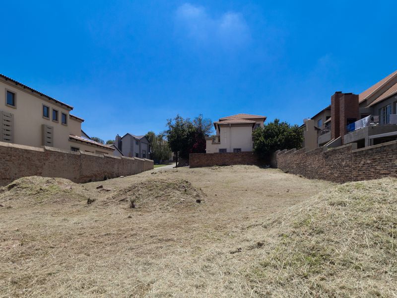 A vacant residential plot situated between existing brick boundary walls, offering a clear space for potential development.