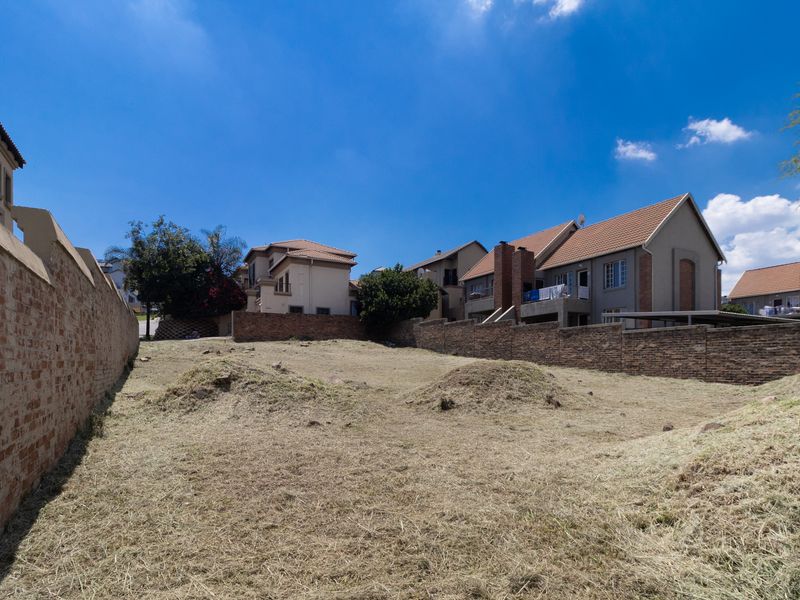 A vacant residential plot featuring a brick boundary wall, ready for development within an established neighborhood setting.