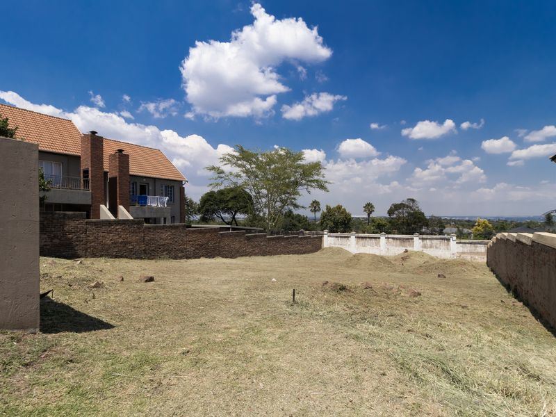 A vacant residential plot featuring established brick boundary walls and perimeter fencing, offering a clear space for future development.