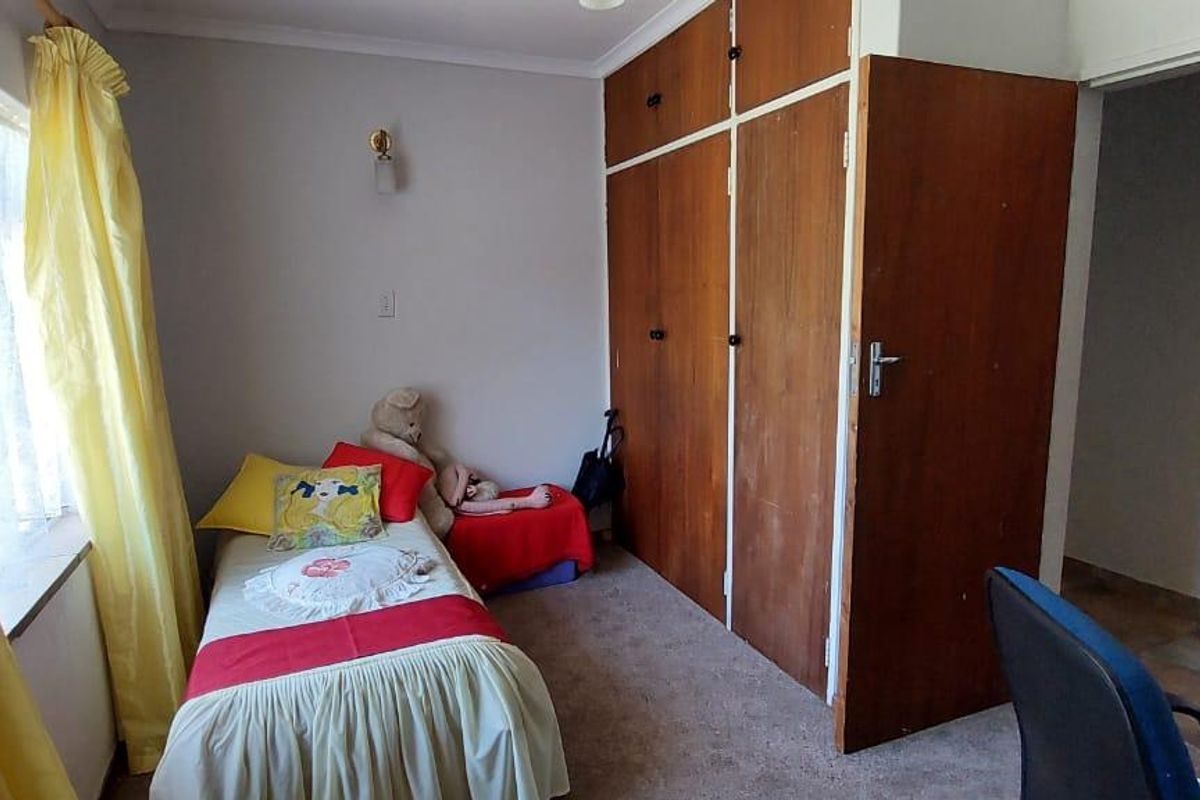 A bedroom featuring built-in wooden cupboards and carpeted flooring, offering a functional space with natural light from the window.