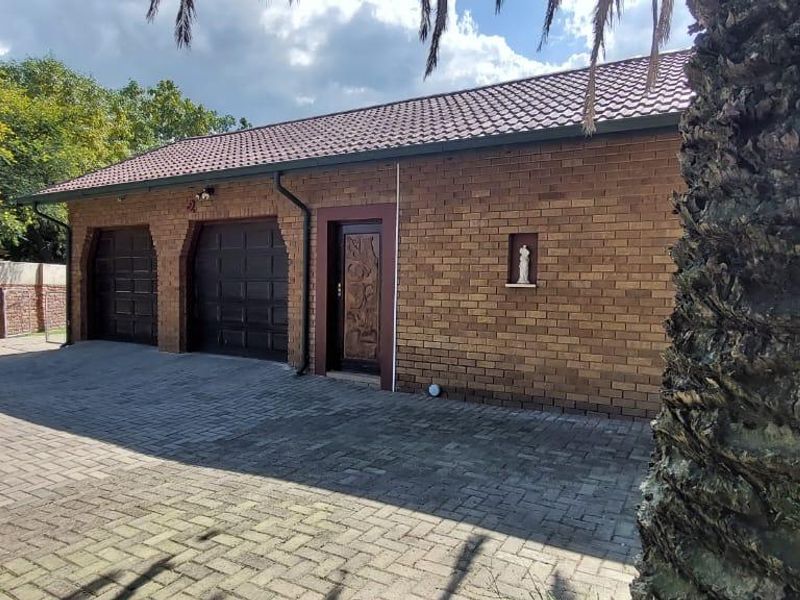 A brick-faced exterior view of a double garage with a paved driveway and a side entrance door.