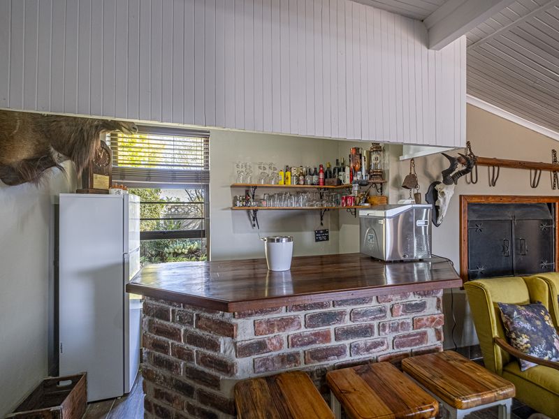 A rustic home bar area featuring a brick-base counter with a timber top, open shelving, and a vaulted timber-paneled ceiling.