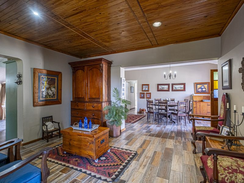 Spacious open-plan living and dining area featuring warm wood-look floor tiles and a classic timber tongue and groove ceiling.