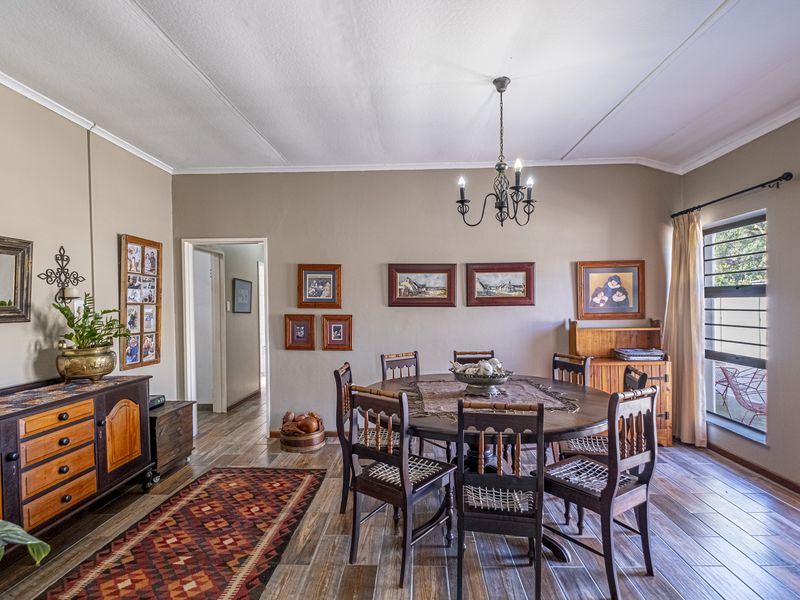 A dining room featuring wood-look tile flooring, a central chandelier, and natural light from a side window.