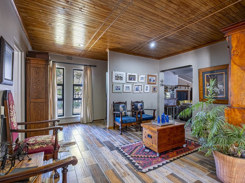 A living area featuring a warm timber tongue and groove ceiling, wood-look tiled flooring, and recessed lighting, creating a cozy and inviting atmosphere.