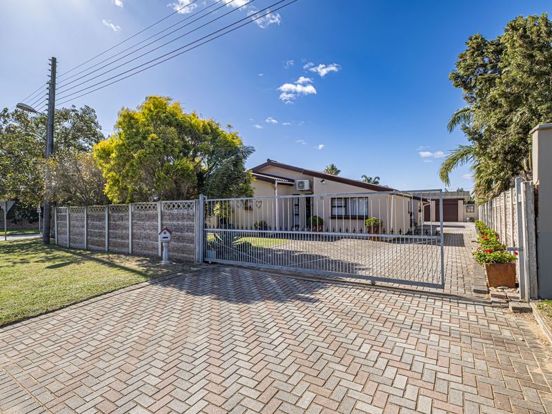Front view of the property featuring a paved driveway, secure sliding metal gate, and a well-maintained exterior facade with an installed air conditioning unit.