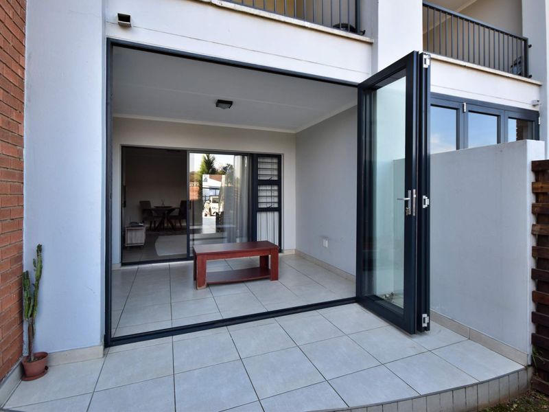 A covered patio area featuring tiled flooring, bi-fold glass doors, and a sliding door providing seamless access to the interior living space.