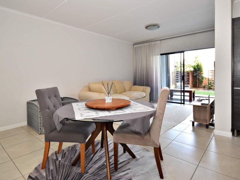Open-plan living and dining area featuring neutral tiled flooring and large sliding glass doors providing direct access to the outdoor patio and garden.