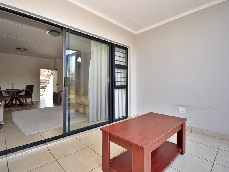 A covered patio area featuring tiled flooring and large sliding glass doors providing seamless access to the interior living space.