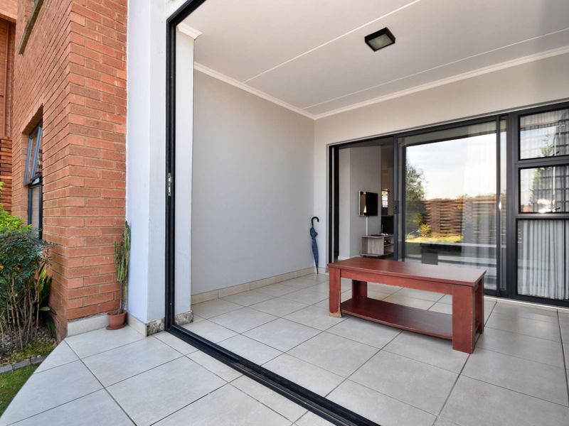A covered patio area featuring tiled flooring and large sliding glass doors that provide seamless access to the interior living space.