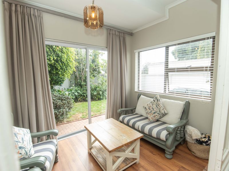 A bright living area featuring laminate flooring, large sliding glass doors opening to the garden, and neutral wall finishes.