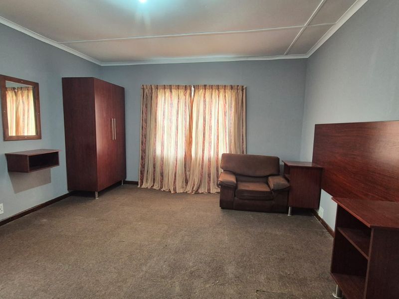 A spacious bedroom featuring carpeted flooring and neutral wall tones, offering a functional layout ready for personalization.