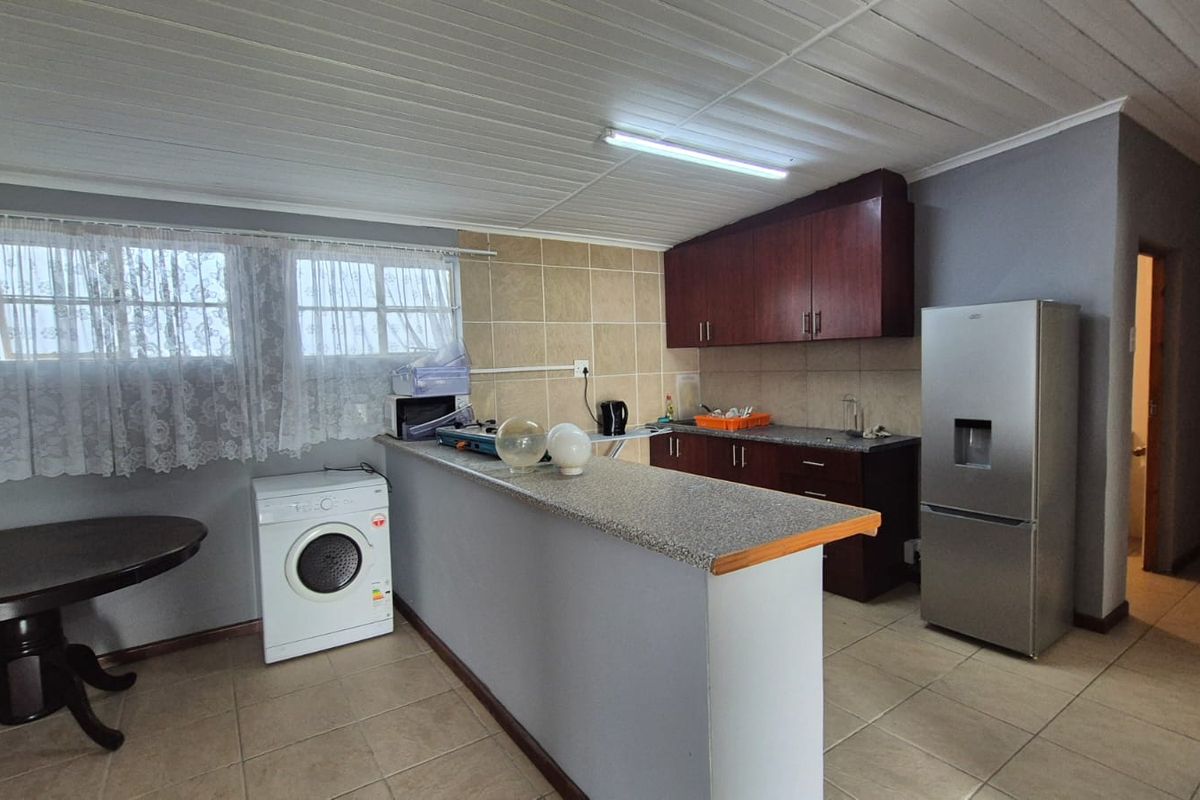 Functional kitchen featuring built-in cabinetry, granite countertops, a breakfast bar, and tiled flooring, providing a practical layout for daily meal preparation.