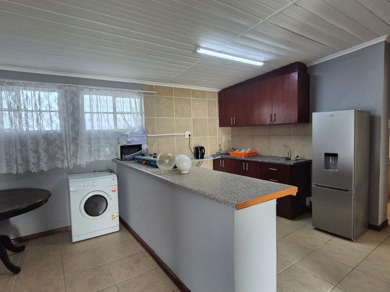 Functional kitchen featuring built-in cabinetry, granite countertops, a breakfast bar, and tiled flooring, providing a practical layout for daily meal preparation.