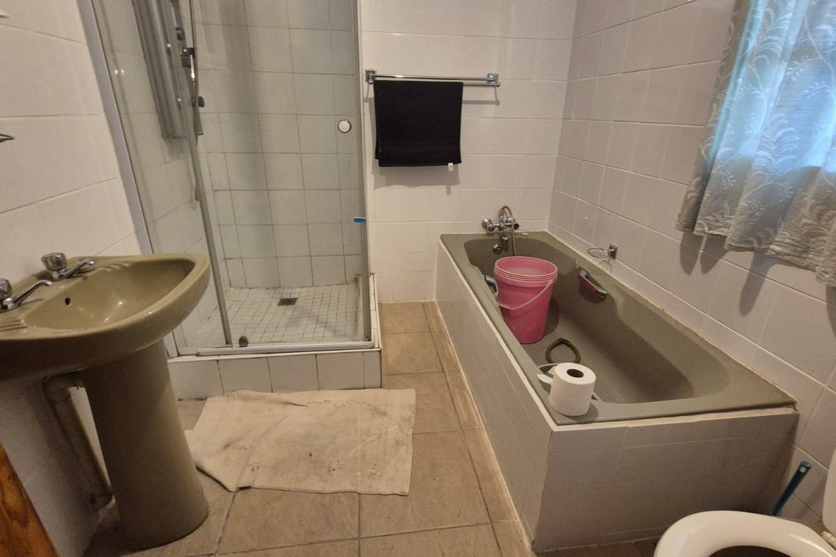 A dated bathroom featuring a pedestal basin, shower enclosure, and built-in bathtub with tiled finishes throughout.