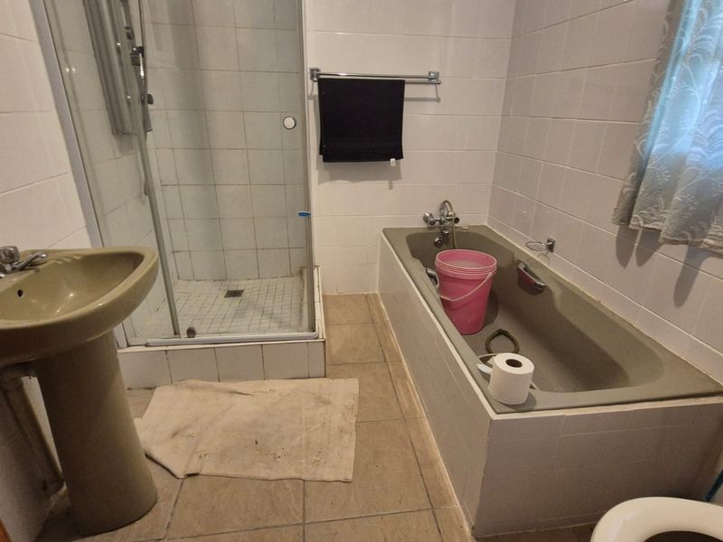 A dated bathroom featuring a pedestal basin, shower enclosure, and built-in bathtub with tiled finishes throughout.