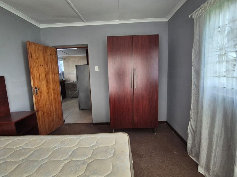 A bedroom featuring carpeted flooring, a built-in cupboard, and a view through to an adjacent tiled room.