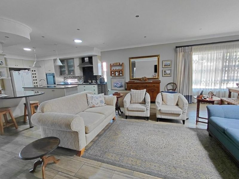 Spacious open-plan living area featuring a modern kitchen with a central island, tiled flooring, and recessed lighting, seamlessly flowing into the lounge space.