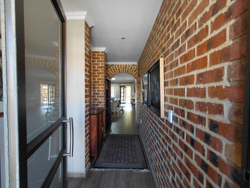 Welcoming entrance hall featuring a striking exposed brick wall, a classic brick archway, and modern tiled flooring leading into the main living area.
