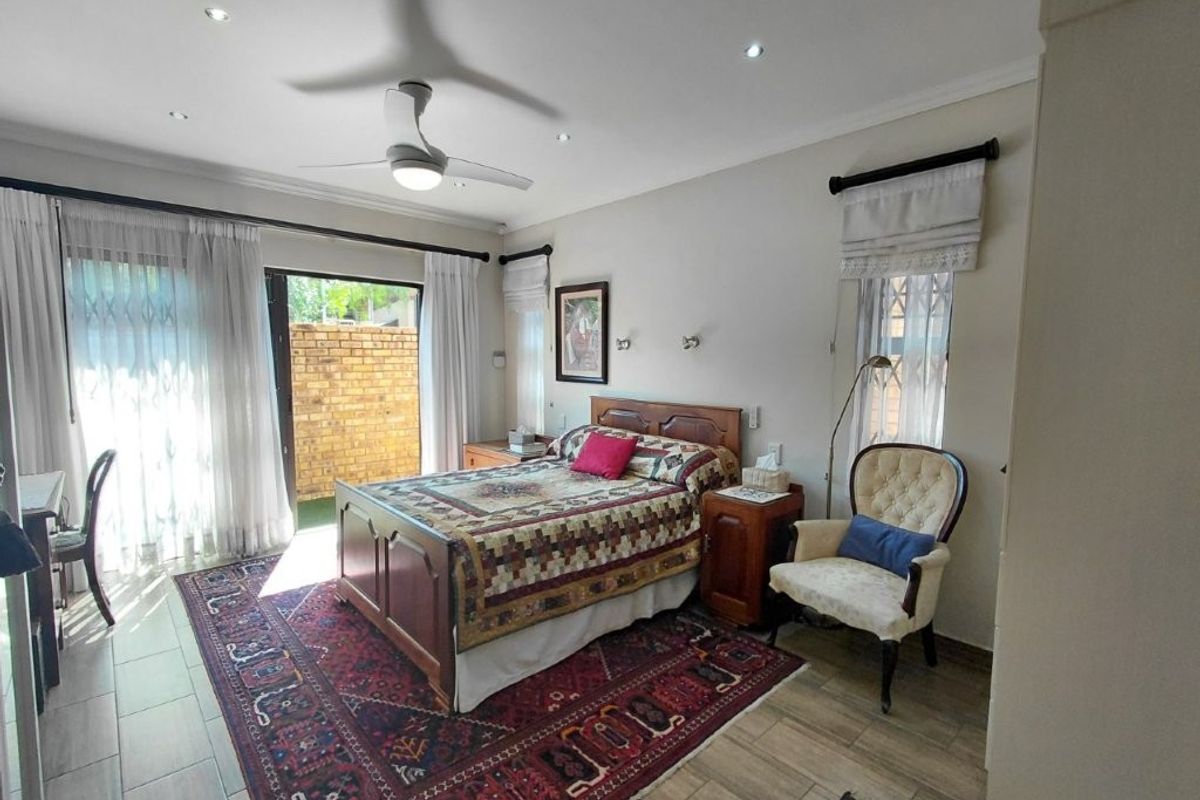 A well-lit bedroom featuring tiled flooring, a ceiling fan, and direct access to an outdoor area through a sliding glass door.