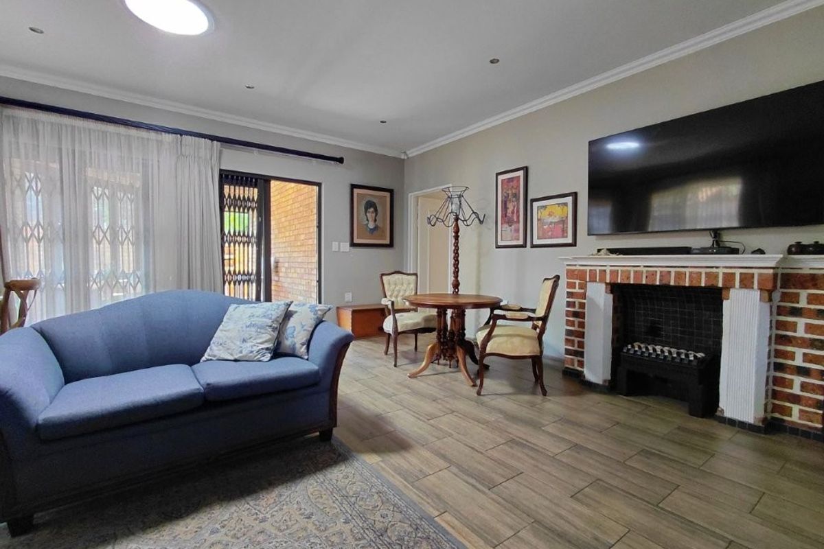 Spacious living room featuring a brick fireplace, tiled flooring, recessed lighting, and a sliding door providing access to the outdoor area.