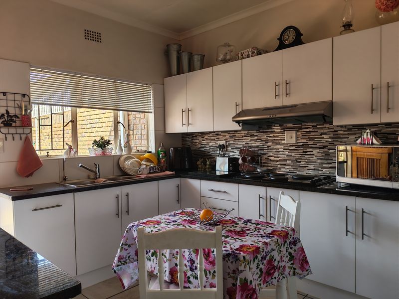 A functional kitchen featuring white cabinetry, dark countertops, a mosaic tiled backsplash, and a built-in hob with an extractor fan.