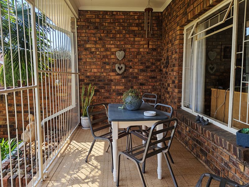 A covered patio area featuring exposed brick walls, security bars, and tiled flooring, providing a functional outdoor space for relaxation.