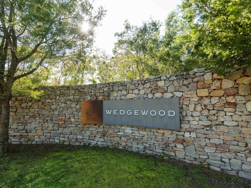 A well-maintained stone boundary wall featuring the Wedgewood estate signage, set within a landscaped garden environment.