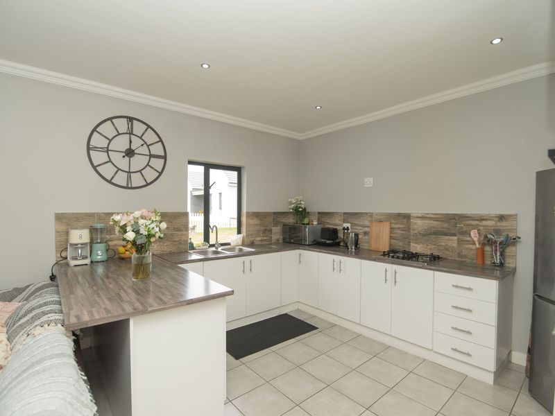 Modern kitchen featuring white cabinetry, wood-look laminate countertops, tiled splashback, gas hob, and tiled flooring with recessed lighting.