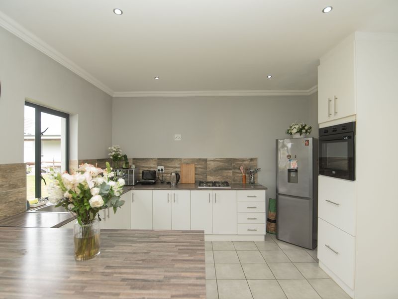 Modern kitchen featuring white cabinetry, wood-look laminate countertops, tiled backsplash, built-in oven, gas hob, and tiled flooring with recessed lighting.
