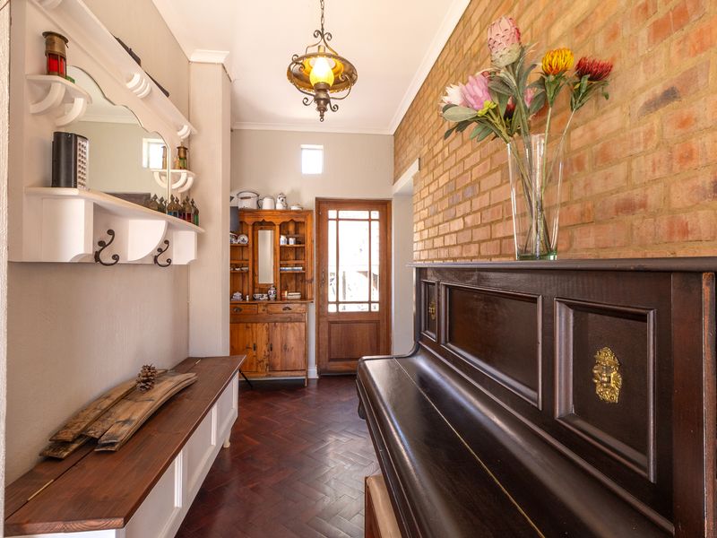 Welcoming entrance hall featuring classic herringbone parquet flooring, a warm exposed brick feature wall, and a traditional timber front door.