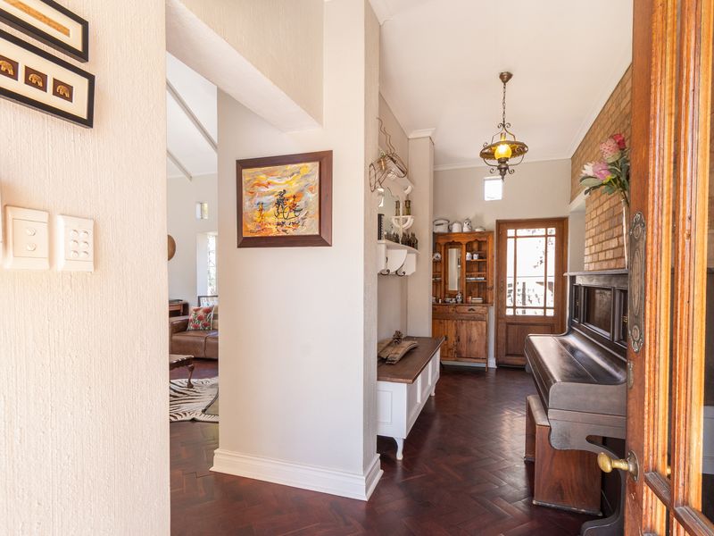 Welcoming entrance hall featuring classic herringbone parquet flooring, an exposed brick feature wall, and a warm, inviting atmosphere leading into the main living area.