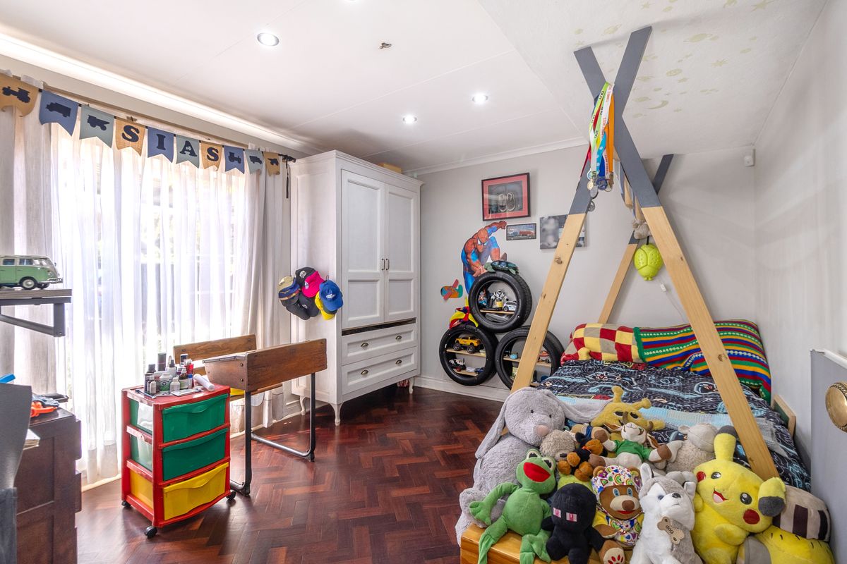 A well-maintained bedroom featuring classic parquet flooring, recessed ceiling lighting, and a built-in wardrobe, offering a functional and comfortable living space.