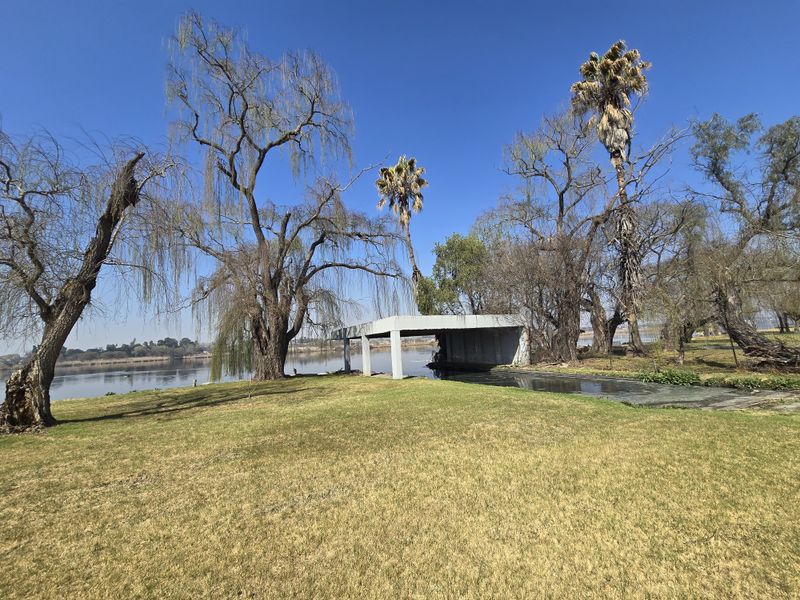 A waterfront view of a small holding featuring a concrete boat house or jetty structure set against a natural landscape with mature trees.