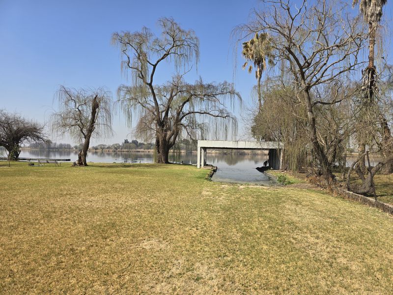 A scenic view of the property's waterfront area, featuring a concrete boat slip or jetty structure set against a large dam or lake.