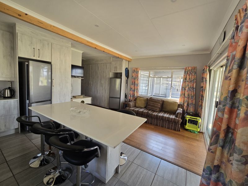 Open-plan living area featuring a modern kitchen with a central island, tiled flooring, and a seamless transition to the lounge space.