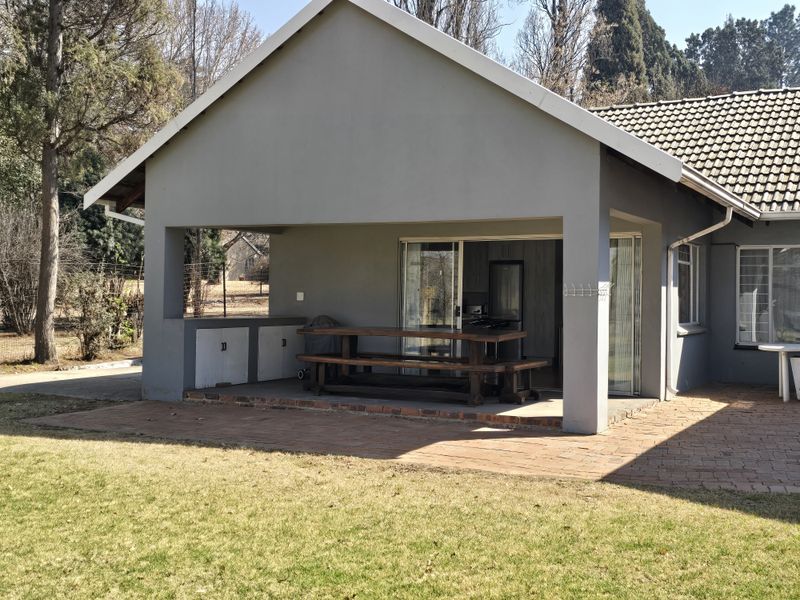 A covered patio area featuring built-in cabinetry and brick paving, providing a functional outdoor entertainment space overlooking the garden.