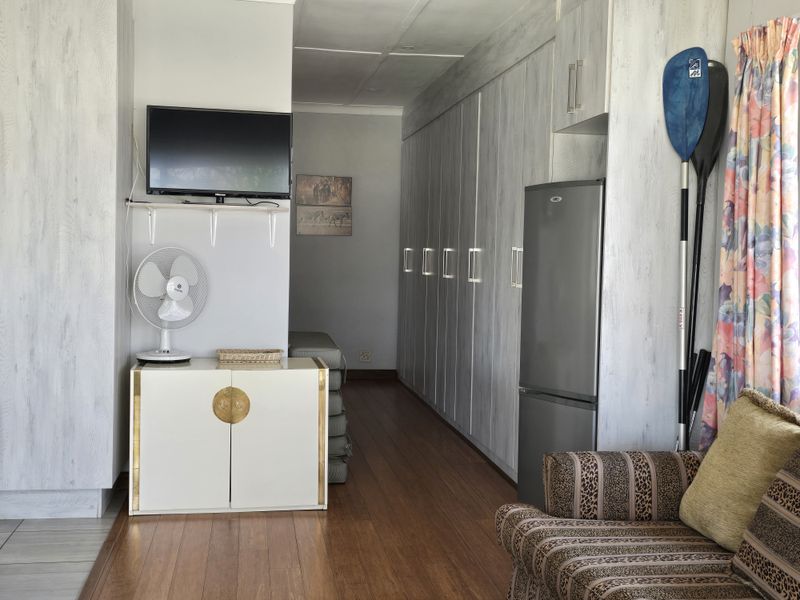 A functional living space featuring extensive built-in cabinetry, wood-look flooring, and a neutral interior finish.