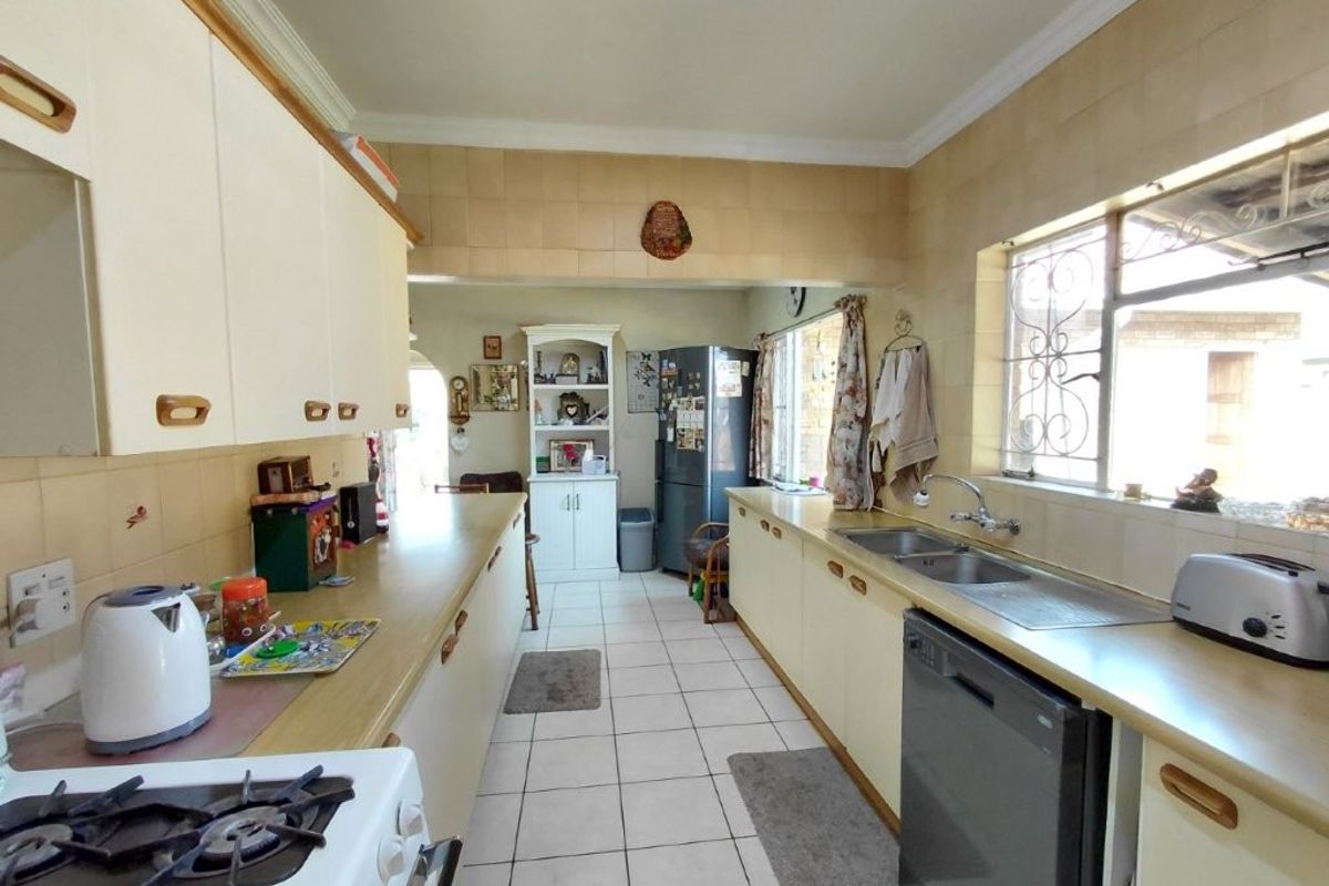 A functional kitchen featuring built-in cabinetry, a double basin sink, tiled backsplash, and gas stove, offering a practical layout with potential for modernization.
