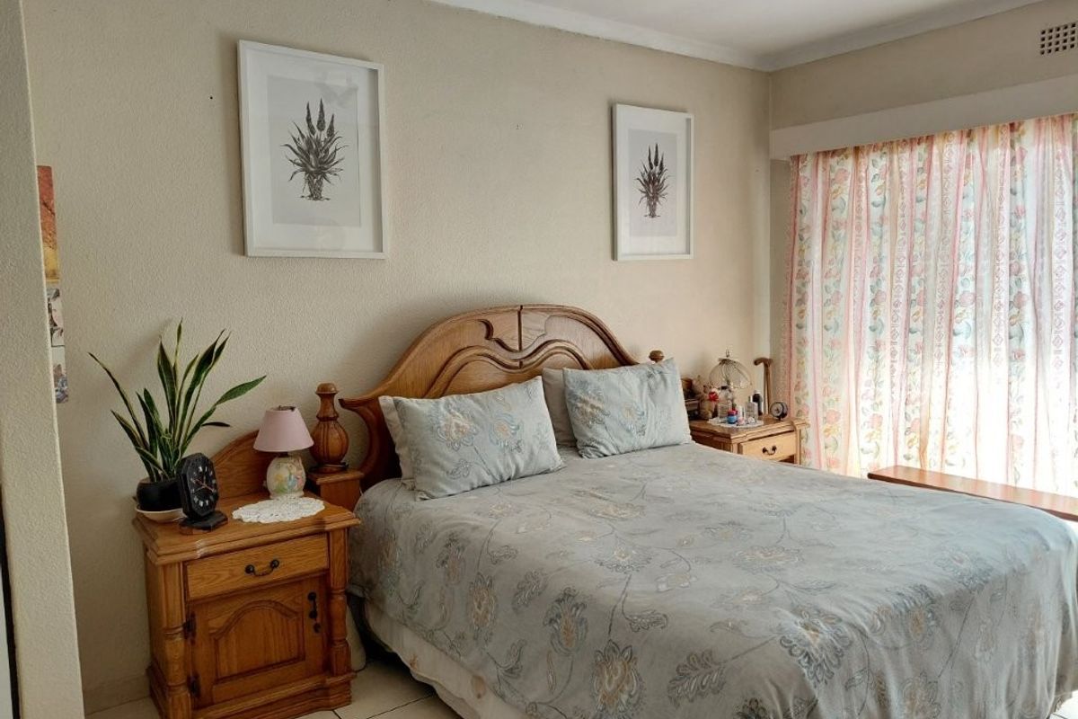 A functional bedroom featuring tiled flooring and a large window with curtain rails, offering a neutral base for potential interior updates.