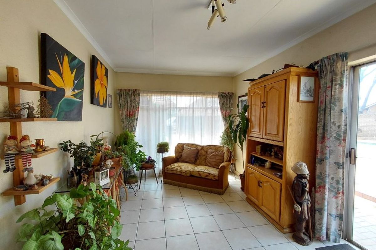 A living room featuring tiled flooring, a ceiling-mounted spotlight track, and a sliding glass door providing access to the exterior.
