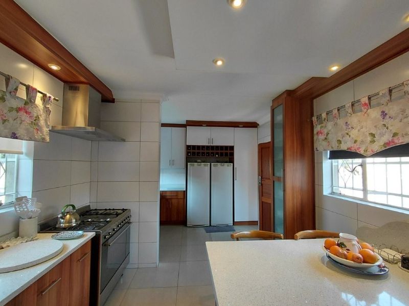 A well-maintained kitchen featuring stone countertops, built-in cabinetry with integrated wine storage, a gas stove with extractor fan, and modern recessed lighting.