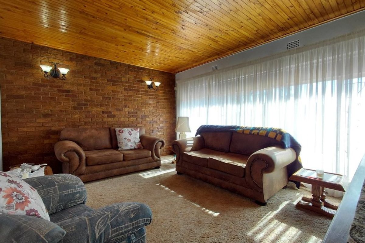 A living room featuring a distinctive exposed brick wall and a warm timber-paneled ceiling, providing a cozy and traditional aesthetic.
