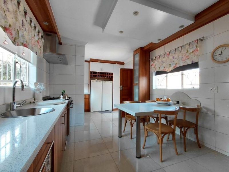 A functional kitchen featuring built-in cabinetry, stone countertops, a stainless steel sink, and integrated storage with a dedicated dining area.