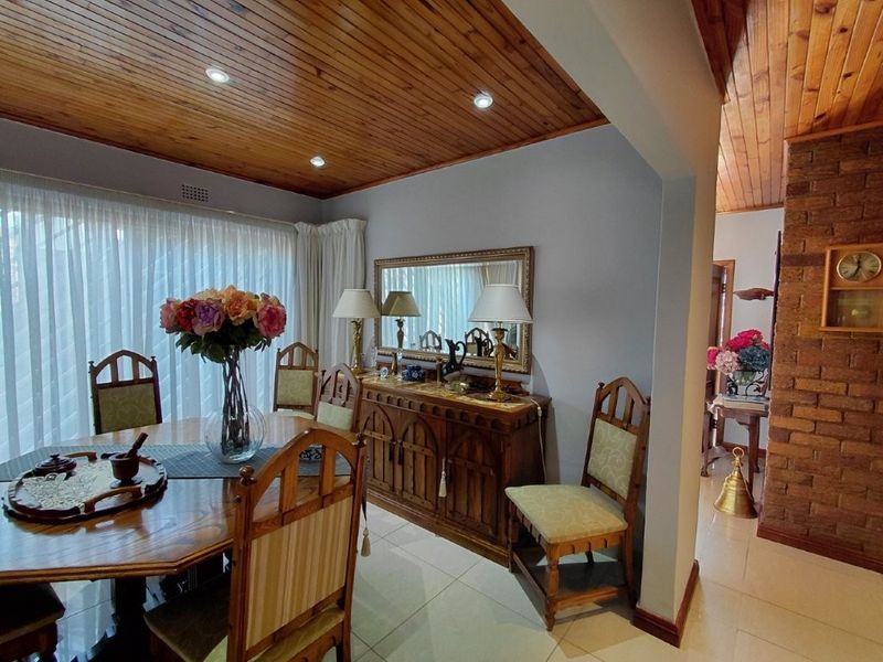 Dining room featuring a warm timber tongue and groove ceiling, recessed lighting, tiled floors, and an exposed brick feature wall.