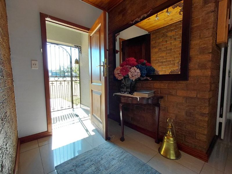 Entrance foyer featuring exposed brick walls, timber ceiling, and tiled flooring, providing a warm and welcoming transition into the home.