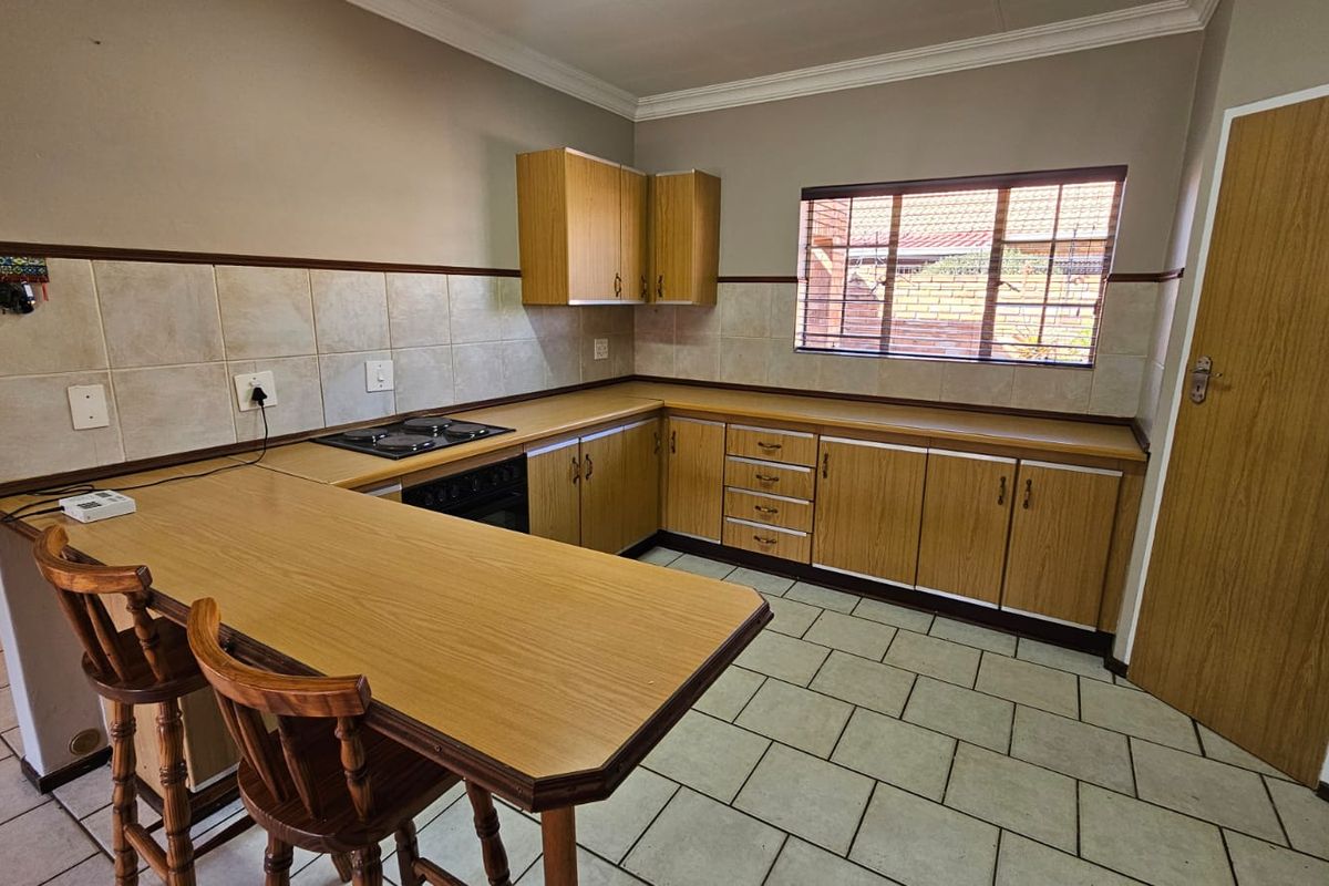 Functional kitchen featuring laminate cabinetry, built-in oven, electric hob, tiled backsplash, and a breakfast bar counter.